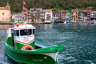 Sailboats moored on river by buildings in city