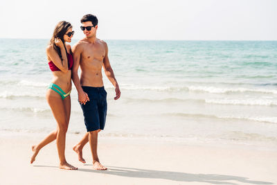 Full length of shirtless man standing on beach