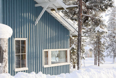 A soft blue cottage in winter covered in snow