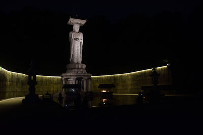 Statue against illuminated building at night