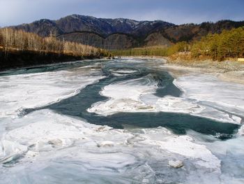 Scenic view of river by mountains against sky