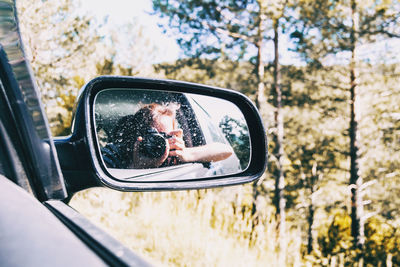 Reflection of man on side-view mirror