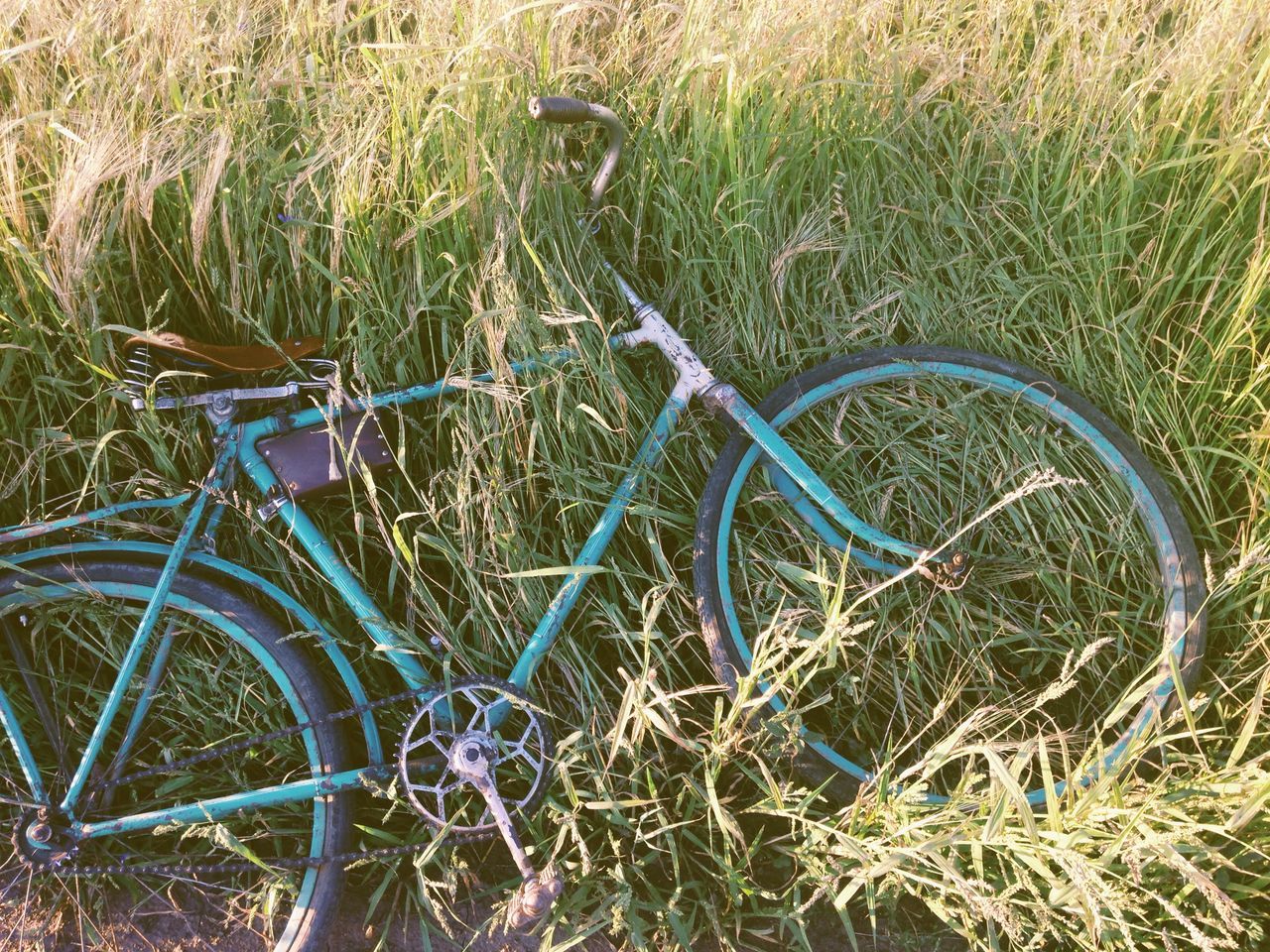 bicycle, grass, high angle view, transportation, mode of transport, field, metal, wheel, abandoned, land vehicle, day, outdoors, no people, stationary, damaged, plant, old, nature, sunlight, tire