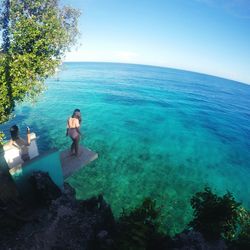 High angle view of female friends standing on diving platform over sea