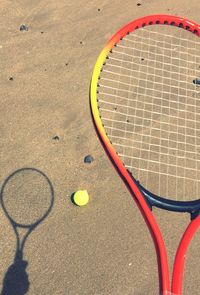 High angle view of tennis racket and ball on sand