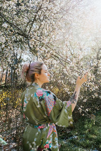 Full length of woman standing by cherry tree