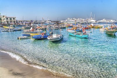 Sailboats moored on sea against clear blue sky