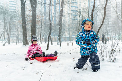 Portrait of smiling woman sitting on snow covered field