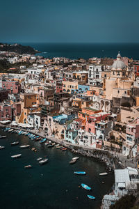 High angle view of illuminated city by sea against sky