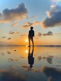 Silhouette man standing on beach against sky during sunset