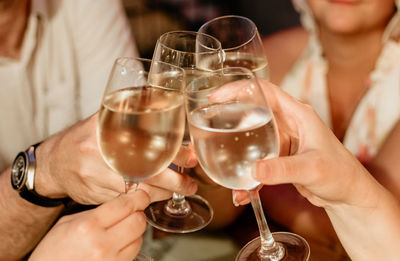 Close-up photo of group of friends clinking glasses with white wine