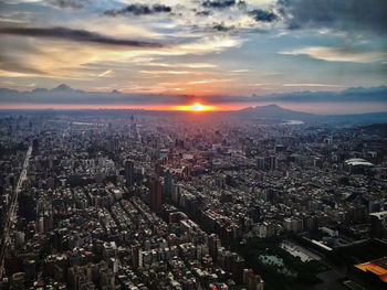 Cityscape against cloudy sky during sunset