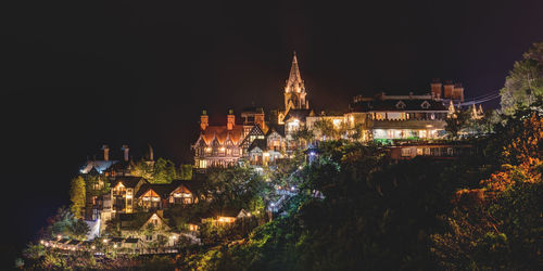 Illuminated house in town on hill at night