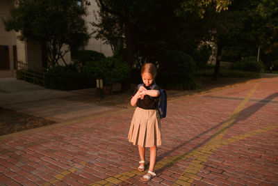 Portrait of young woman walking on footpath