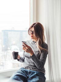 Young woman using mobile phone at home