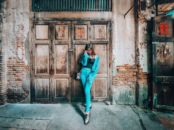 Portrait of woman standing against door