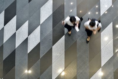 Directly above shot of women walking on flooring in office