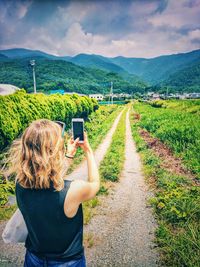 Rear view of woman photographing on field