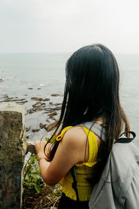 Rear view of woman looking at sea against sky