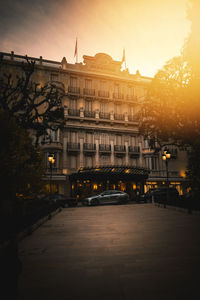 Illuminated street amidst buildings in town at sunset