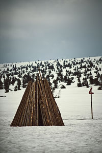 Wooden posts on snow covered land against sky