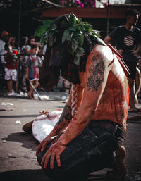 Side view shirtless man bleeding while sitting outdoors