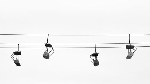 Low angle view of overhead cable cars hanging against clear sky