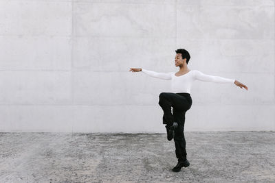 Full length of young man dancing against wall