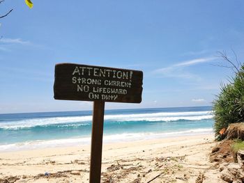 Information sign on beach against sky
