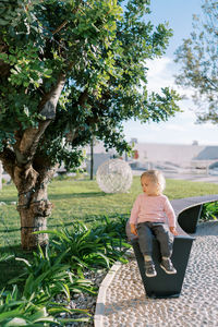 Portrait of young woman sitting on tree