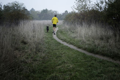 Rear view of man jogging with dog on land