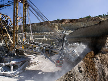 Earth mover on mining mountain against clear sky