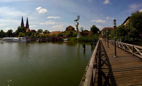 Bridge over river by buildings against sky