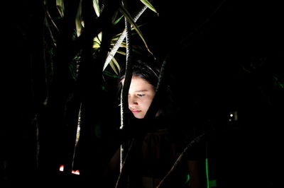 Close-up of girl standing by plant during night