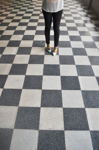 Low section of woman standing on checked tiled floor