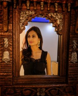 Beautiful woman looking away while reflecting in mirror 