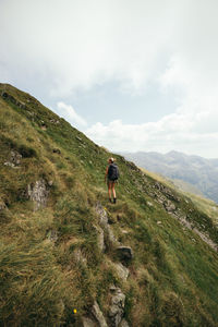 Rear view of woman standing on mountain against sky