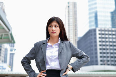 Worried businesswoman with hands on hip standing in city