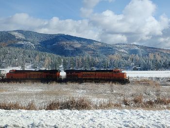 Built structure on field by snowcapped mountains against sky