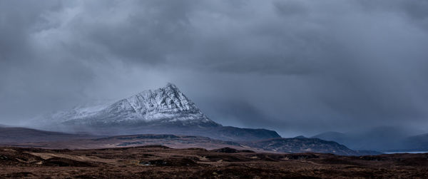 Scenic view of snowcapped mountains against cloudy sky