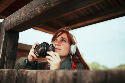 Portrait of young woman photographing through camera