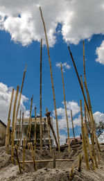 Low angle view of wooden posts on beach against sky