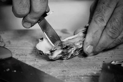 Cropped image of man eating oyster from shell on cutting board