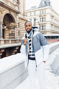 Young african man on street, snow winter season, city portrait