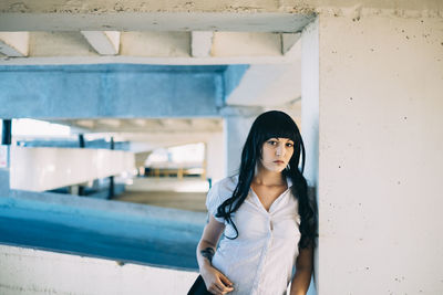 Portrait of young woman standing against wall