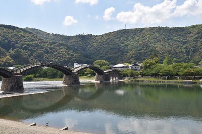 Bridge over river by mountains against sky