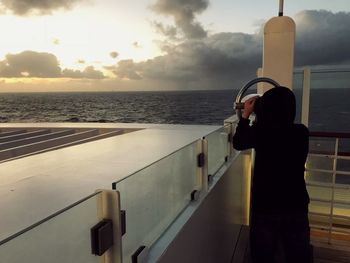 Man and woman standing by sea against sky during sunset