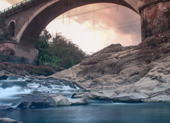 Arch bridge over river against sky