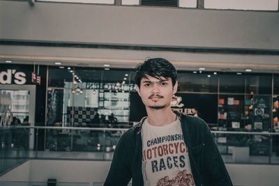 Portrait of young man standing against wall