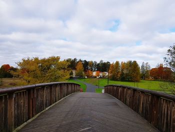 Footpath amidst trees against sky during autumn